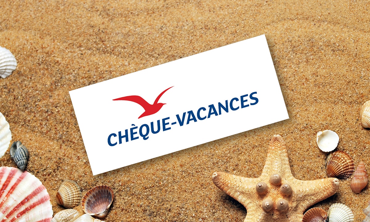 Photo d'un chèque vacances ANCV sur du sable avec une étoile de mer et des coquillages