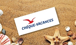 Photo d'un chèque vacances ANCV sur du sable avec une étoile de mer et des coquillages